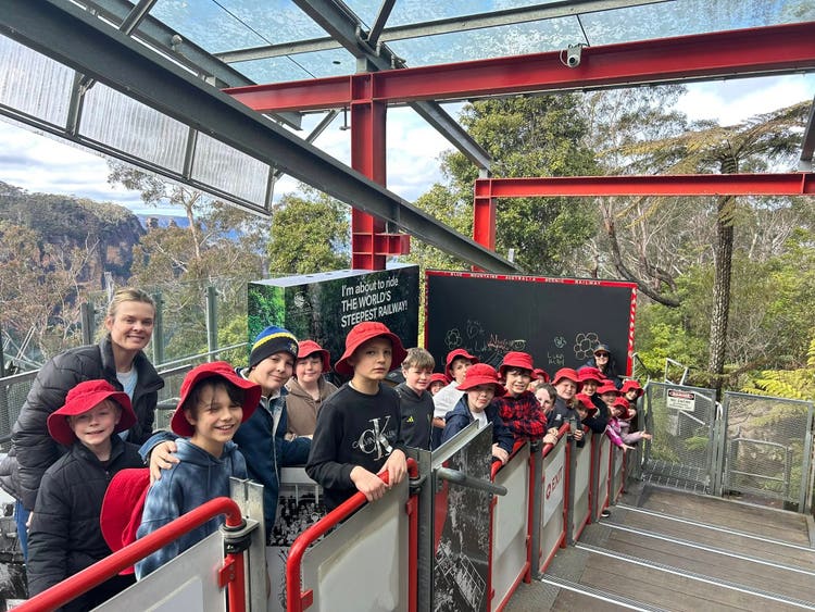 Students and teacher posing for a photo whilst waiting to get on a ride